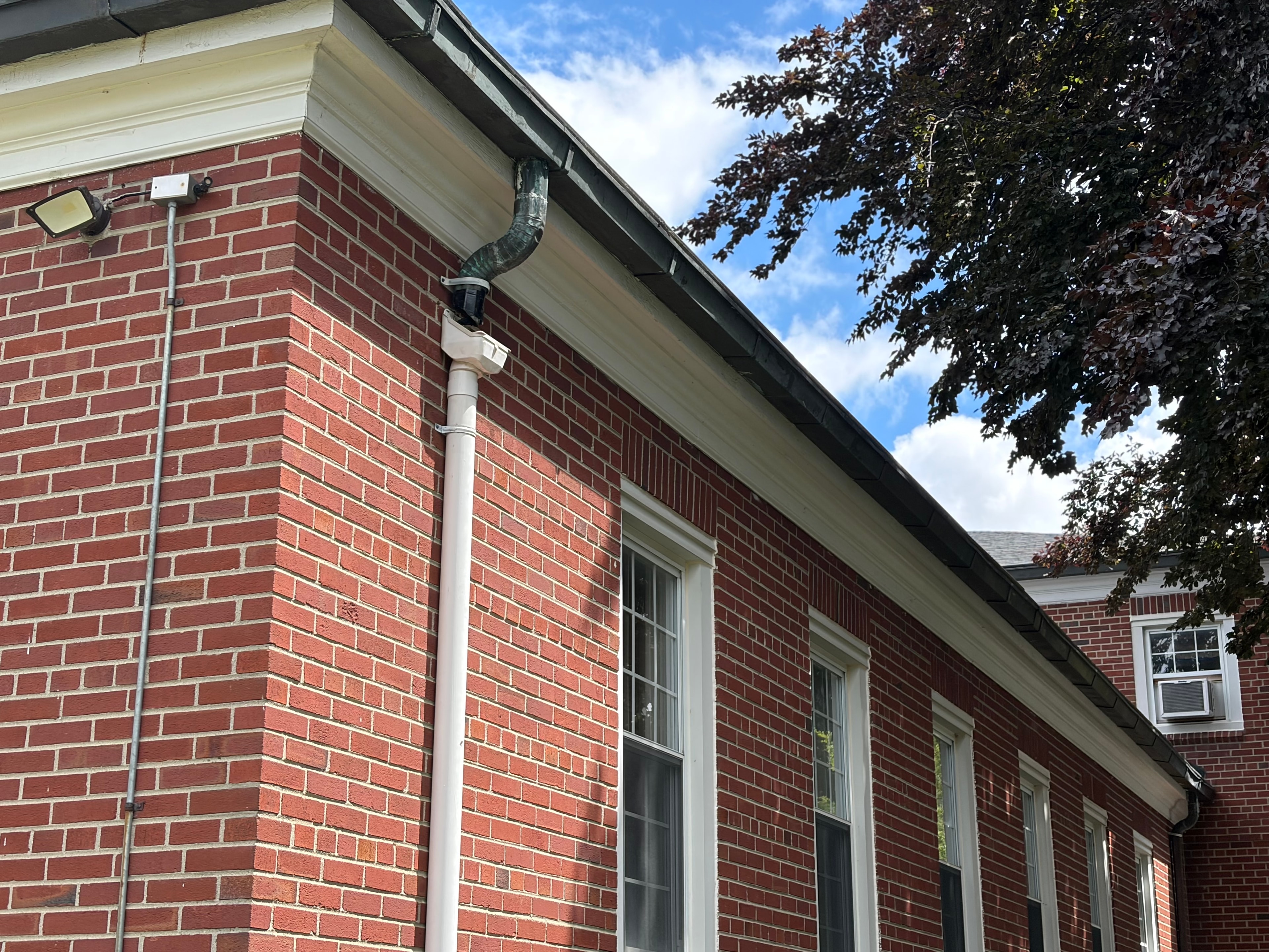 Copper downspout and gutter corner on brick church exterior