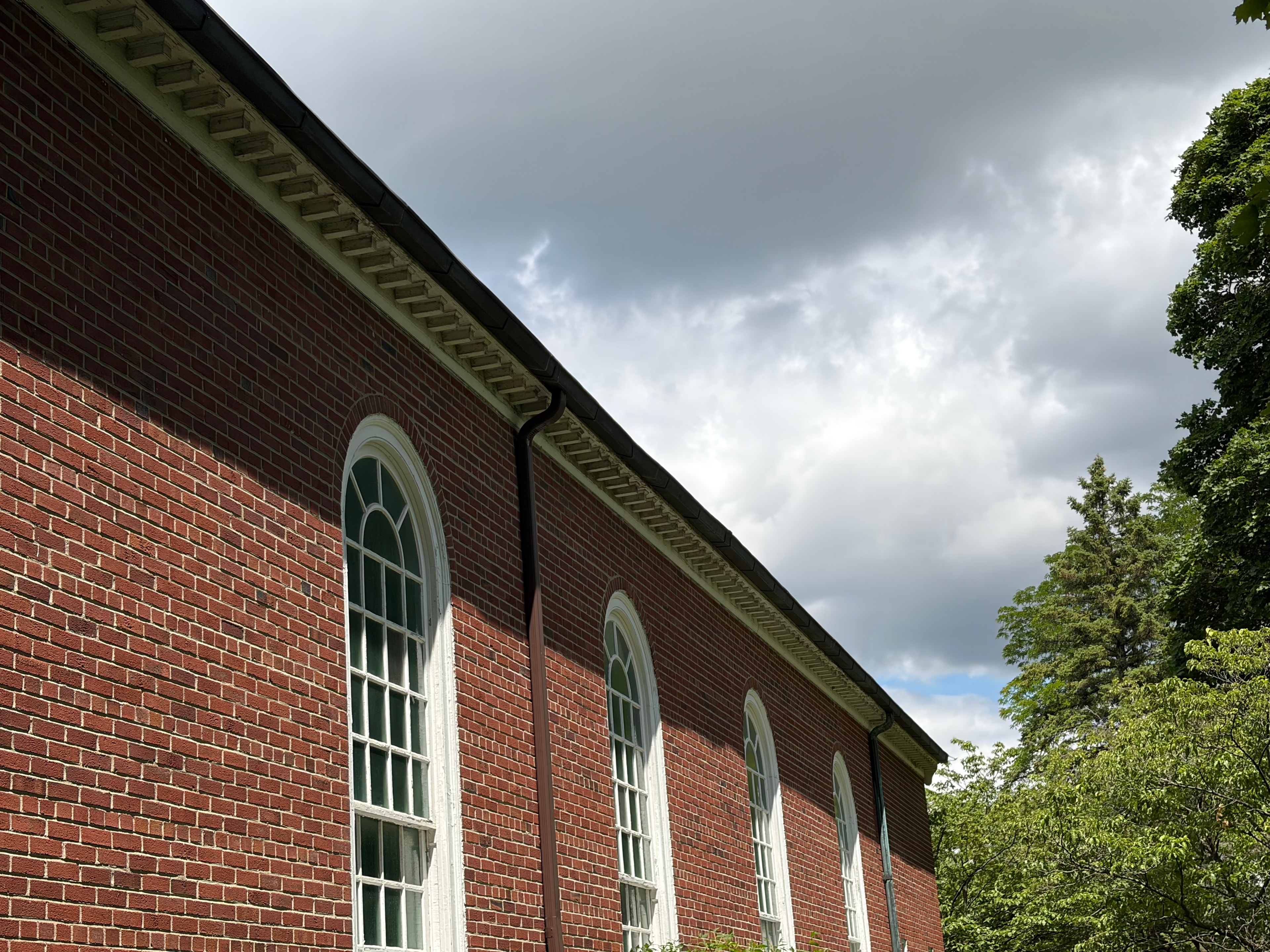 Wide view of historic brick church exterior with full copper gutter run